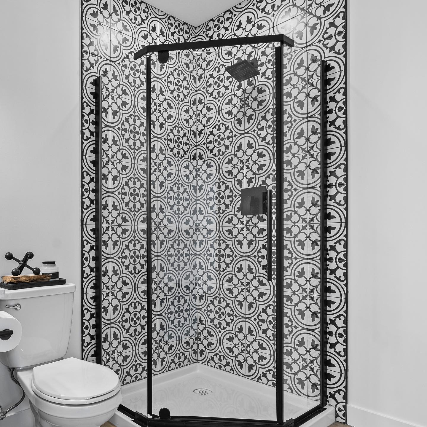 Basement bathroom with patterned tile shower and matte black fixtures
