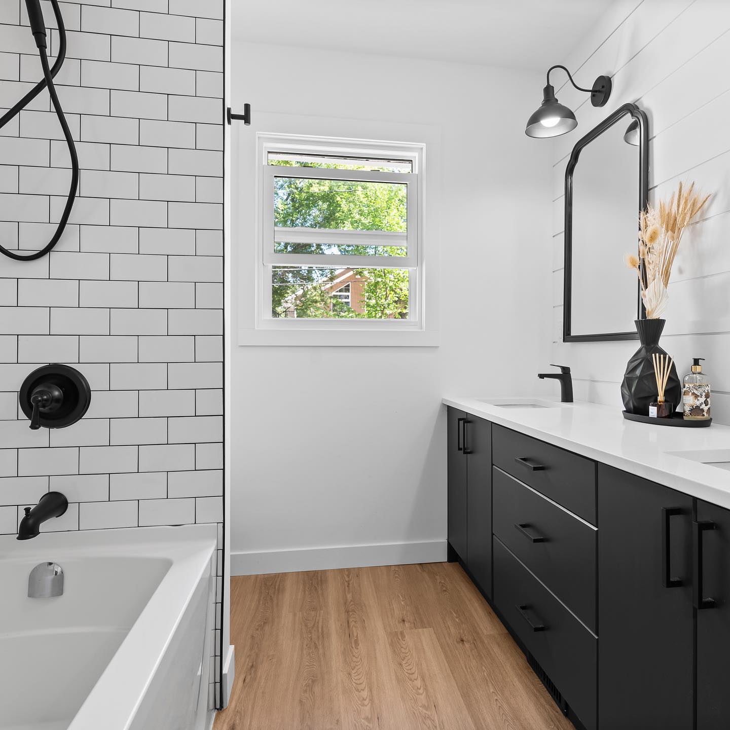 Renovated bathroom with subway tile, wood-look floor, and black vanity