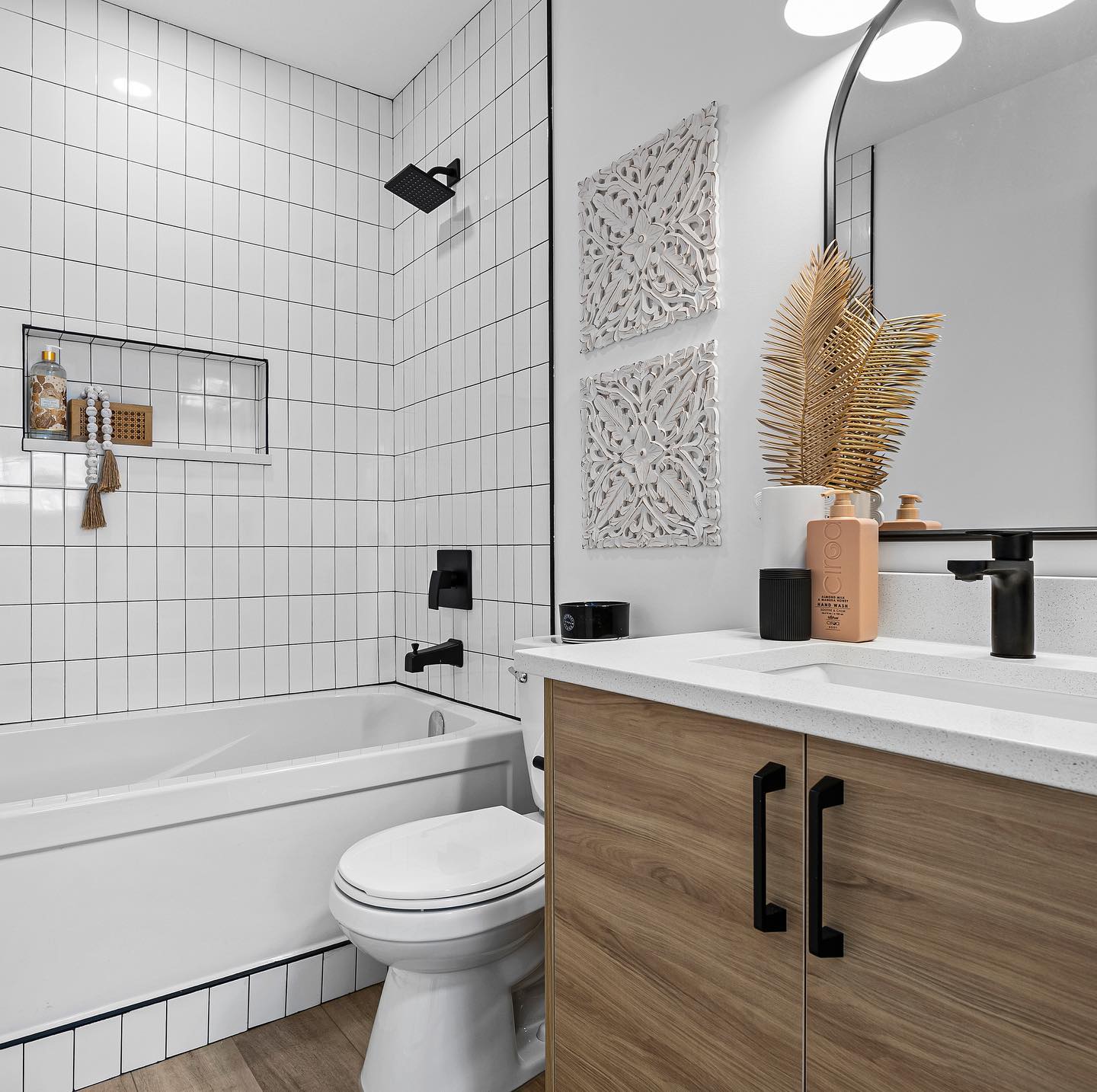 Renovated bathroom with white tile, wood vanity, and black fixtures
