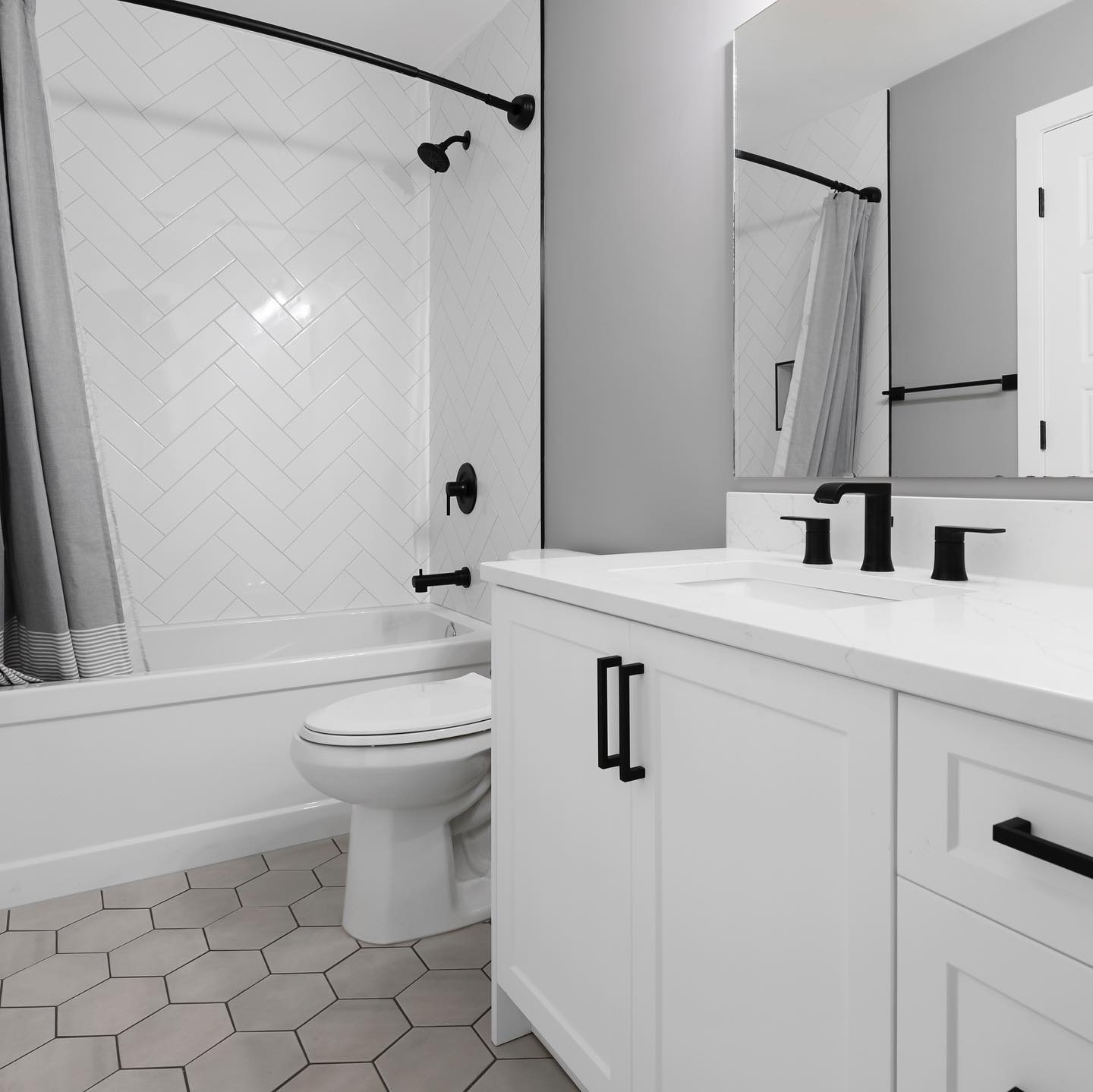 Bright bathroom renovation with white tile, vanity, and matte black fixtures